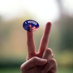 person holding blue and white UNK pin back button